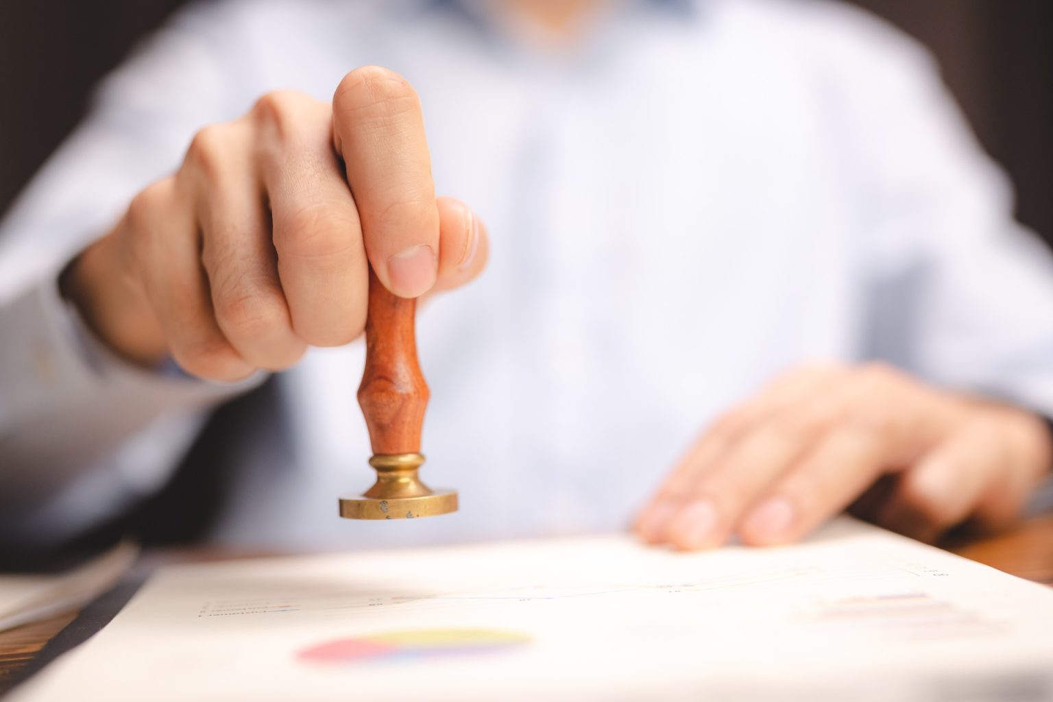hand stamping with approved stamp on certificate document public paper at desk, notary or business